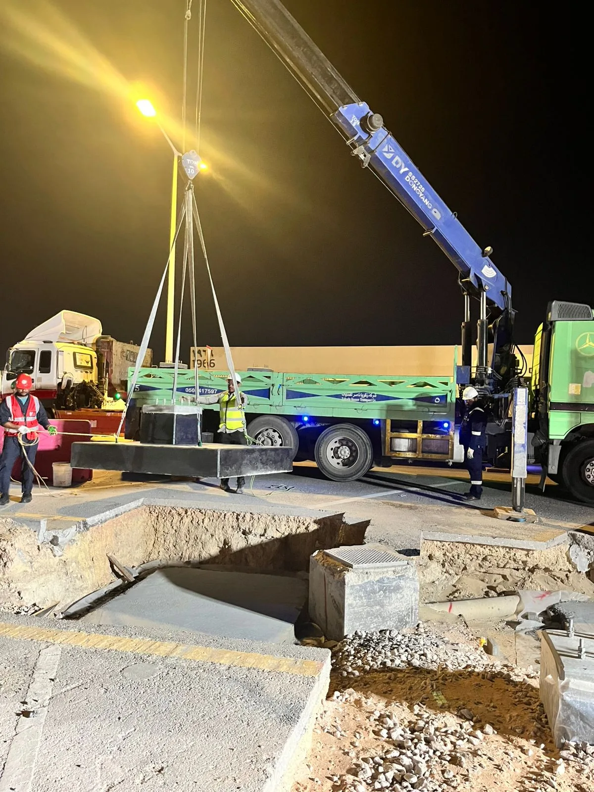 Crane lifting structural materials during night-time site work